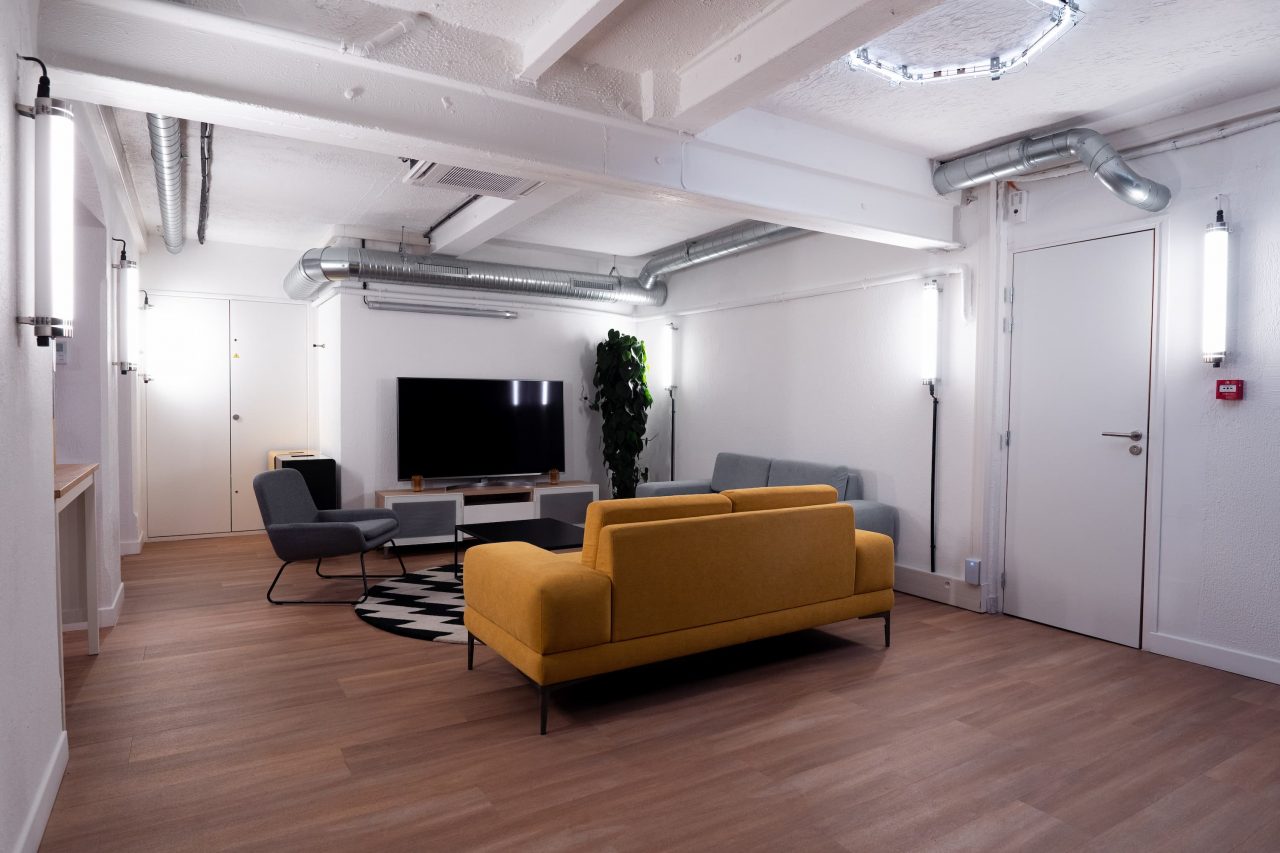 Espace lounge de V.Hive avec canapés tapis et télé